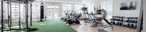a gym with weights and a tv on the wall