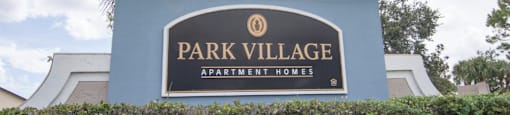 The main sign at Park Village- sign reads "Park Village Apartment Homes"- blue sign