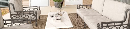 A small patio with a white couch, chair, and coffee table.