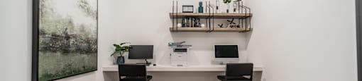 an office with a desk and two chairs and a painting on the wall