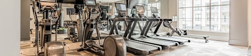 A spacious gym with a variety of equipment including treadmills, elliptical machines, and a stationary bike.