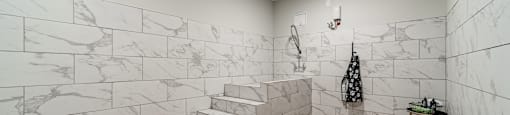 A bathroom with marble tiles on the walls and wooden flooring.