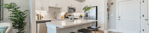 A modern kitchen with a white island and bar stools.