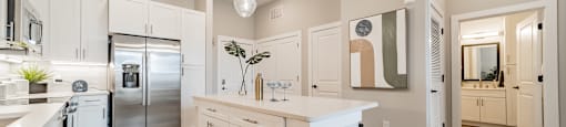 A modern kitchen with wooden floors and white cabinets.