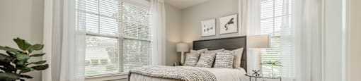 a bedroom with a bed and two windows