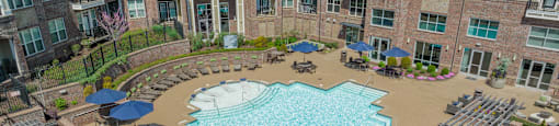 an aerial view of a resort style pool with lounge chairs and umbrellas in front of