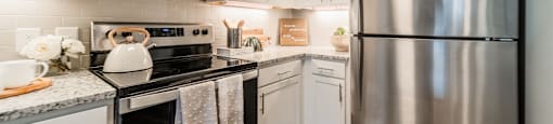 an updated kitchen with stainless steel appliances and white cabinets