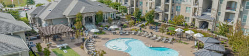 an aerial view of a swimming pool and patio area with apartment buildings