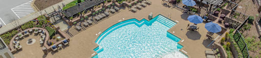 a large swimming pool with lounge chairs and umbrellas