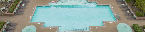 an aerial view of a large swimming pool with umbrellas and chairs around it