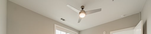 A spacious room with a ceiling fan and carpeted floor.
