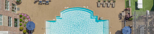 an aerial view of a large swimming pool with umbrellas and grassy areas surrounding it