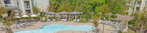 a view of a pool and a poolside patio with tables and umbrellas