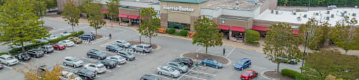 an aerial view of a parking lot filled with cars and a shopping center
