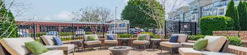 a seating area with chairs and a fire pit in the middle of a brick patio