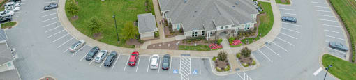 an aerial view of an apartment complex with parking lot and cars