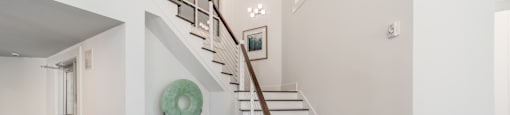 a stairway in a house with white walls and a green plate on the floor