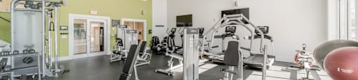 a spacious fitness center with exercise equipment and windows