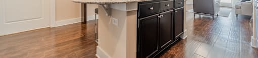 a kitchen with an island and a living room in the background