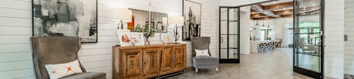 the lobby of a home with two chairs and a wooden cabinet