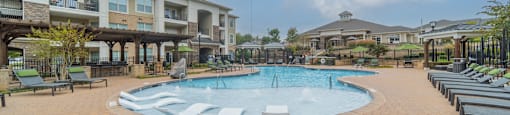 a resort style pool with lounge chairs and buildings in the background