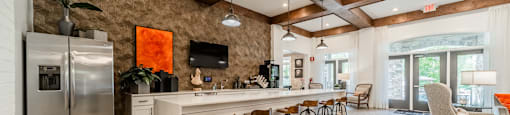 a kitchen with a long island with bar chairs and a refrigerator
