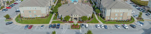 an aerial view of an apartment complex with a swimming pool and parking lot
