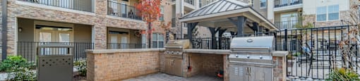 an outdoor kitchen with a grill and a gazebo in an apartment complex