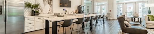 the gathering room and kitchen of a new home with a large island and chairs