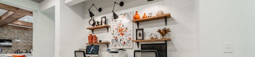 a home office with desks and chairs and a white brick wall