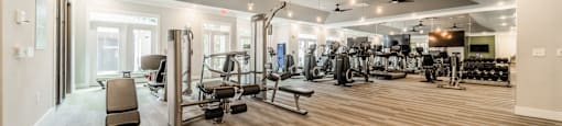 a gym with cardio equipment and weights on a wooden floor