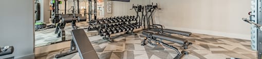 A spacious gym with a variety of equipment including treadmills, weights, and a flat screen TV.