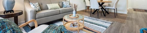 A living room with a grey couch, a coffee table, and a painting on the wall.