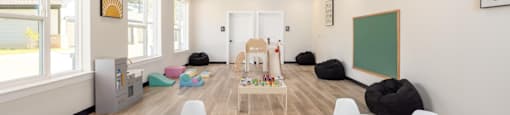 A room with a white table and chairs with a black bean bag on the floor at Liam at Hays Farm in Huntsville, Alabama