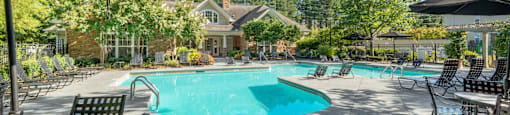 A sunny day at the pool with chairs and umbrellas.