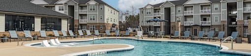 A large swimming pool in front of apartment buildings.