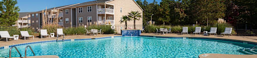 A large swimming pool in front of a building with a blue sky in the background.