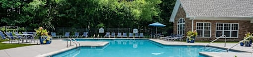 A large outdoor swimming pool surrounded by trees and a building.