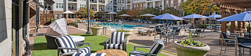 A sunny day at the poolside with chairs and umbrellas.