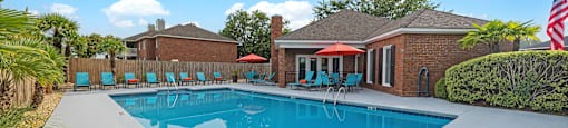 A swimming pool in a backyard with a house and trees in the background.