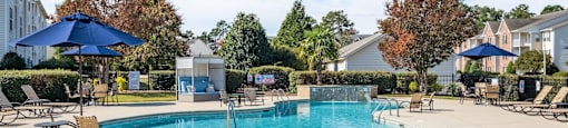 a swimming pool with lounge chairs and umbrellas