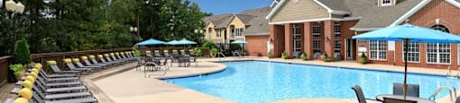 A pool surrounded by lounge chairs and umbrellas.