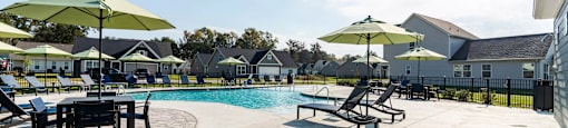 A sunny day at the poolside with green umbrellas and loungers.