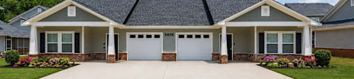 A two-story house with a grey roof and a white garage door.