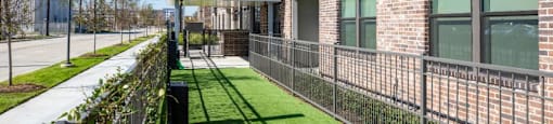 a grassy area with a fence in front of a brick building