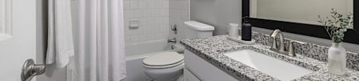 A bathroom with a toilet, sink, and shower.