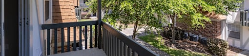 A balcony with a view of a tree and a house.