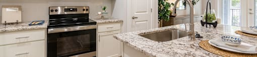 a kitchen with white cabinets and granite counter tops and stainless steel appliances