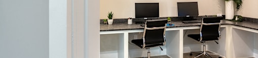 a business center with three desks and chairs and paintings on the wall