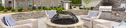 the patio has a fire pit and chairs with blue and white striped pillows
